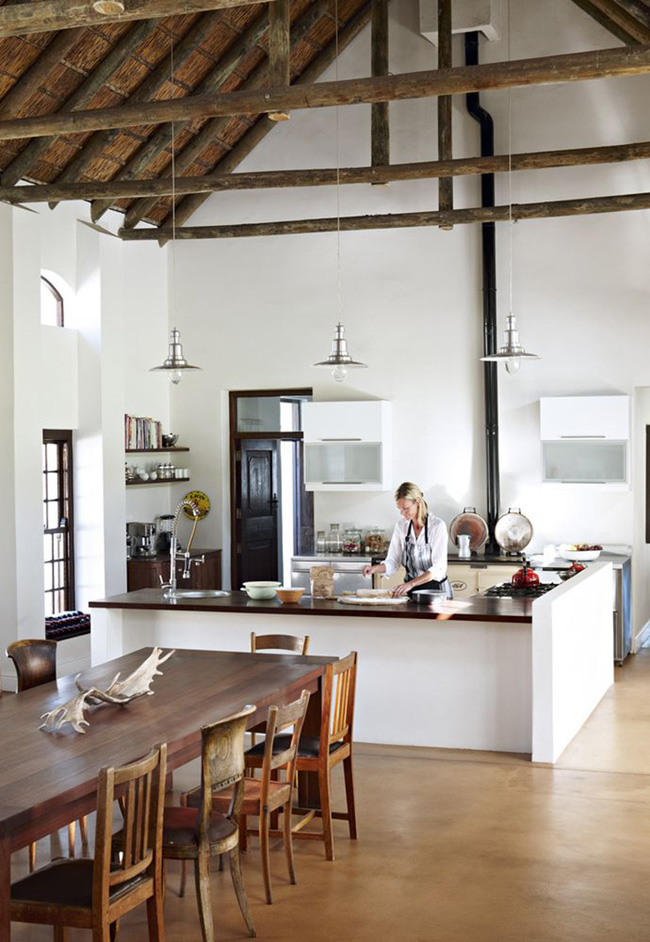 Phòng bếp theo phong cách trang trại hiện đại với một lò sưởi và không gian phòng ăn mộc mạc với những chiếc ghế khác nhau.