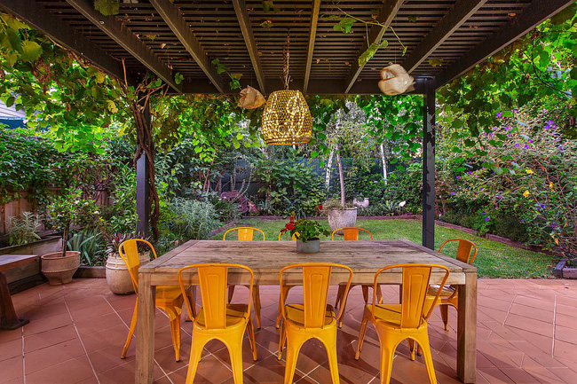 Bàn gỗ cùng bộ ghế màu vàng chanh chói mắt được đặt ngoài hiên nhà, nơi có khung cảnh thiên nhiên vô cùng choáng ngợp.